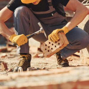 Construction worker in uniform and safety equipment sits and have job on building