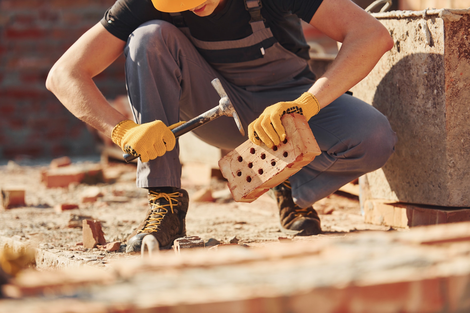 Construction worker in uniform and safety equipment sits and have job on building