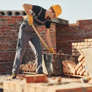 Using showel. Construction worker in uniform and safety equipment have job on building